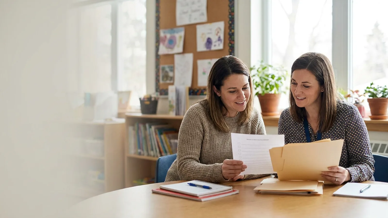 Parent reviewing school support notes with a teacher at a classroom table.