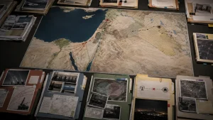 Overhead view of a large strategic map surrounded by folders, photos, and planning documents on a table.